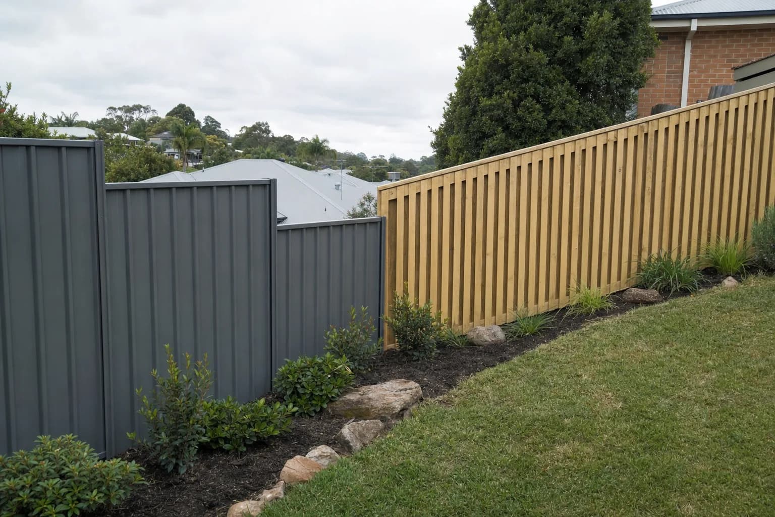 A stepped Colorbond fence beside a raked timber fence on sloping Launceston blocks, showing the difference in the top line