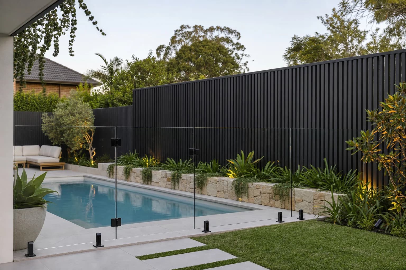 Glass pool fence and aluminium slat screen in a landscaped Launceston backyard